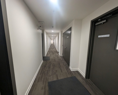 Newly painted ceiling, walls and baseboards in apartment building hallways and common areas.